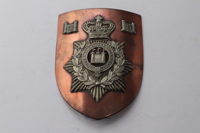 Lot 717 - Victorian 1st Cambridgeshire Rifle Volunteer Corps other ranks helmet plate, mounted with two other badges on a copper shield shaped plaque, 17cm overall length