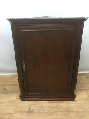 Lot 1076 - George III mahogany hanging corner cupboard, the moulded cornice above a panelled door enclosing shaped shelves, flanked by reeded columns, 104cm high