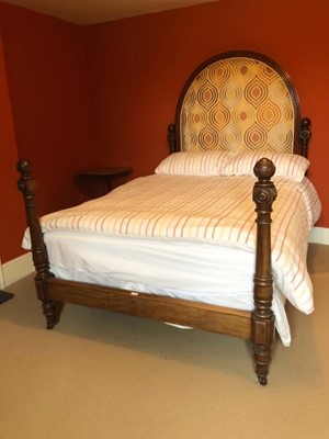 Lot 1531 - Victorian mahogany framed double bedstead, the upholstered arched headboard flanked by carved and turned pillars, matching pillars at the footboard, metal side rails and base, 210cm long x 143cm wi...