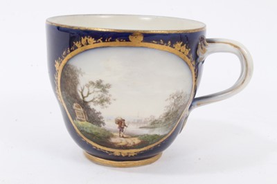 Lot 121 - Four 18th century continental porcelain cups, various marks including crossed swords and interlaced L's, one cup finely painted with a landscape and seascape on a cobalt ground, another with birds...