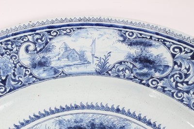 Lot 139 - 19th century Dutch blue and white Delft charger, painted with a figural scene, the edge with landscape reserves on a foliate patterned ground, 'AK' monogram to reverse, 47cm diameter