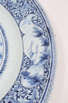 Lot 139 - 19th century Dutch blue and white Delft charger, painted with a figural scene, the edge with landscape reserves on a foliate patterned ground, 'AK' monogram to reverse, 47cm diameter
