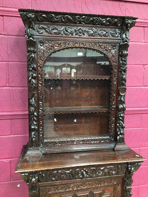 Lot 360 - Late Victorian carved oak two height bookcase with glazed door above enclosing shelves, and geometric panelled door below