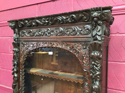 Lot 360 - Late Victorian carved oak two height bookcase with glazed door above enclosing shelves, and geometric panelled door below