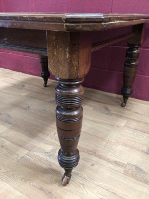 Lot 329 - Edwardian wind-out extending dining table with two extra leaves on turned legs terminating on ceramic castors