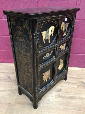 Lot 355 - Oriental lacquered two door cupboard decorated with applied Oriental plaques, 61cm wide, 29.5cm deep, 86.5cm high