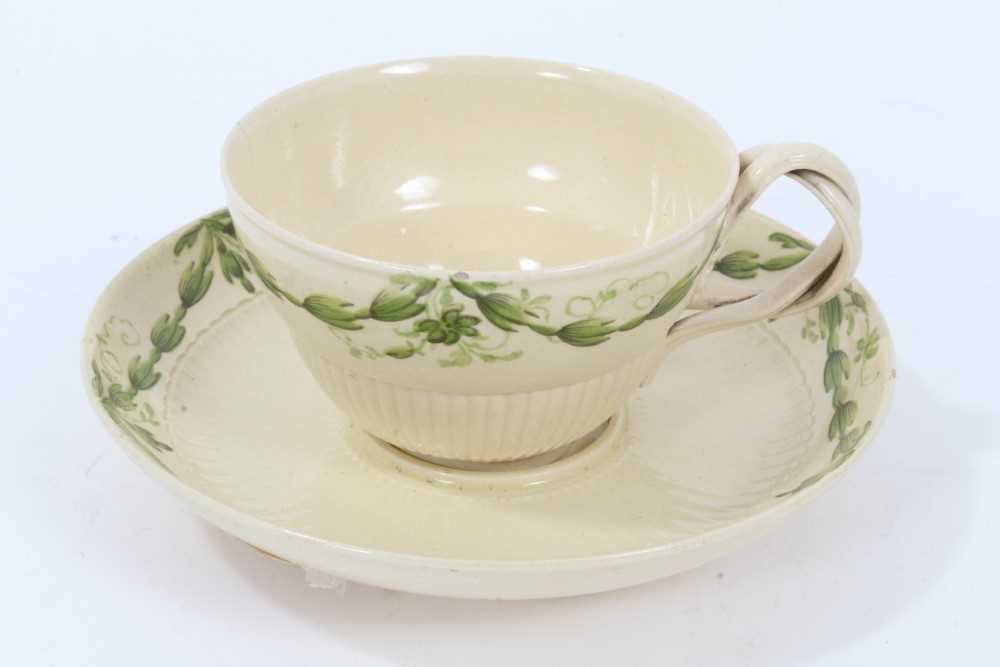 Lot 191 - Leeds creamware tea cup and saucer, c.1780, semi-fluted form, the cup with double strap handle, painted in green enamel with foliate swags, the saucer measuring 12cm diameter