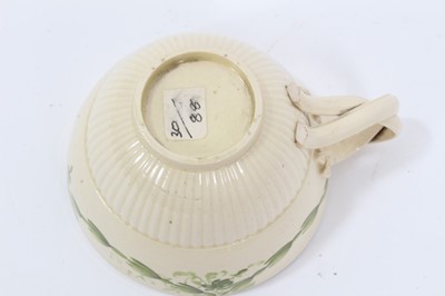 Lot 209 - Leeds creamware tea cup and saucer, c.1780, semi-fluted form, the cup with double strap handle, painted in green enamel with foliate swags, the saucer measuring 12cm diameter