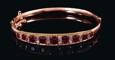 Lot 524 - Late Victorian ruby and diamond hinged bangle with nine graduated oval mixed cut rubies interspaced by rose cut diamonds in gold setting with pierced gallery on gold hinged bangle. In original fitt...