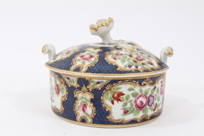 Lot 225 - Worcester butter tub and cover, c.1770, polychrome decorated with flowers within gilt scrollwork cartouches, on a blue scale ground, the cover with flower finial, 10.5cm diameter