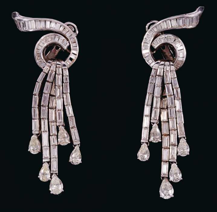 Lot 527 - Pair of Art Deco style diamond pendant earrings with a stylized waterfall design, the baguette cut diamond scroll issuing five articulated drops of further baguette cut diamonds, each suspending a...
