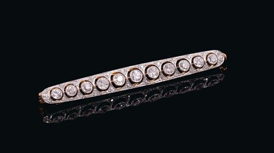 Lot 537 - Edwardian diamond bar brooch with a line of eleven old cut diamonds in openwork circles surrounded by old cut diamonds in platinum millegrain setting on 18ct yellow gold pierced gallery. Estimated...