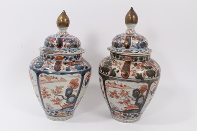 Lot 254 - Near pair of Japanese Edo period Imari vases and covers, decorated with landscapes and flowers, 26.5cm and 28cm high