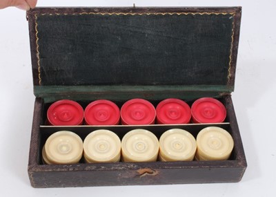 Lot 958 - Set of 30 Victorian turned white and red stained ivory draughts in a tooled leather case.