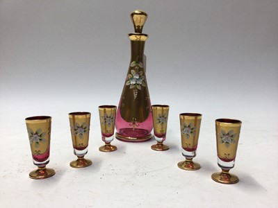 Lot 1090 - Gilt overlaid cranberry glass liquor set comprising decanter with stopper, 26.5cm high and six liquor glasses (7)