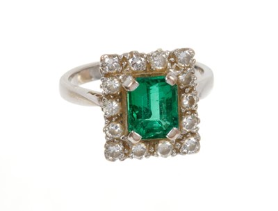 Lot 473 - Emerald and diamond cluster ring with a rectangular step cut emerald surrounded by a border of fourteen brilliant cut diamonds on 18ct white gold shank