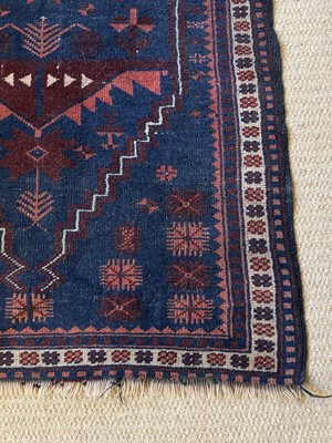 Lot 973 - An antique Eastern rug with geometric medallions on blue and red ground, 130cm x 82cm, together with another on red ground, 118cm x 88cm (2)