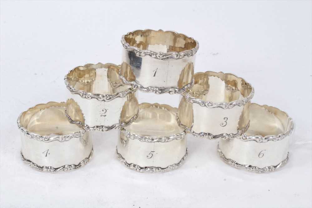 Lot 237 - Set of six Edwardian silver napkin rings, with scroll borders and engraved 1- 6
