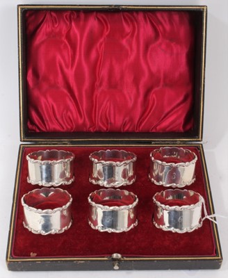 Lot 237 - Set of six Edwardian silver napkin rings, with scroll borders and engraved 1- 6