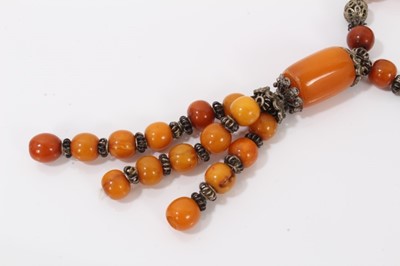 Lot 38 - Amber bead necklace with white metal spacers and tassel terminal
