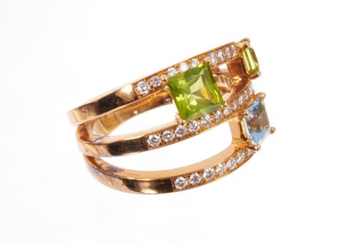 Lot 1968 - A diamond, aquamarine and peridot ‘Satellite’ three-row ring by Ritz Fine Jewellery of London, incorporating a 0.58cts princess cut aquamarine, two princess cut peridots and sixty nine round brilli...