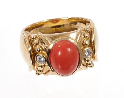 Lot 1975 - Coral and diamond dress ring, the wide 14ct yellow gold band with a central oval coral cabochon flanked by two brilliant cut diamonds in rub-over setting with applied gold beaded decoration. London...