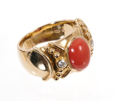 Lot 1975 - Coral and diamond dress ring, the wide 14ct yellow gold band with a central oval coral cabochon flanked by two brilliant cut diamonds in rub-over setting with applied gold beaded decoration. London...