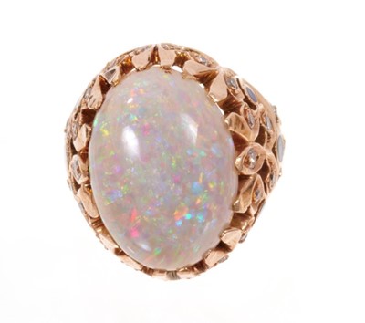 Lot 1980 - Opal, diamond and enamel cocktail ring with a large oval cabochon opal measuring approximately 19mm x 14mm in pierced gold foliate setting with single cut diamonds and black enamel decoration. Fing...
