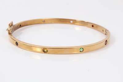 Lot 36 - 9ct gold hinged bangle set with eight multi coloured sapphires