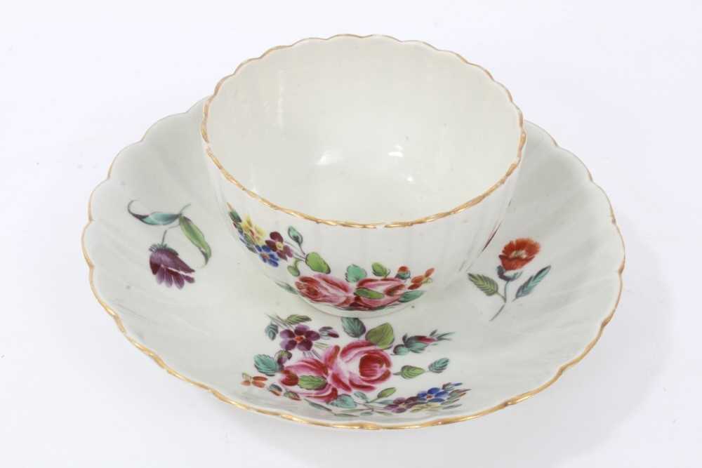 Lot 24 - Worcester fluted tea bowl and saucer, circa 1772, polychrome painted with flowers, with gilt rims, the saucer measuring 13.5cm diameter
