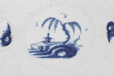 Lot 55 - Worcester blue and white strap-fluted saucer dish, circa 1756, decorated with scrollwork panels containing Chinese landscapes, and foliate patterned rim, 18.5cm diameter