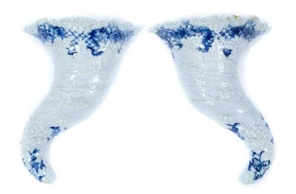 Lot 171 - Rare pair of Worcester cornucopia wall pockets, circa 1755, moulded with landscape scenes, with floral and other patterns in underglaze blue, painter's marks to backs, 21cm long