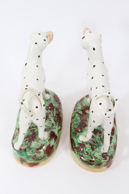 Lot 68 - Pair of Staffordshire pottery models of Dalmatians, shown standing on naturalistic bases, 16cm high