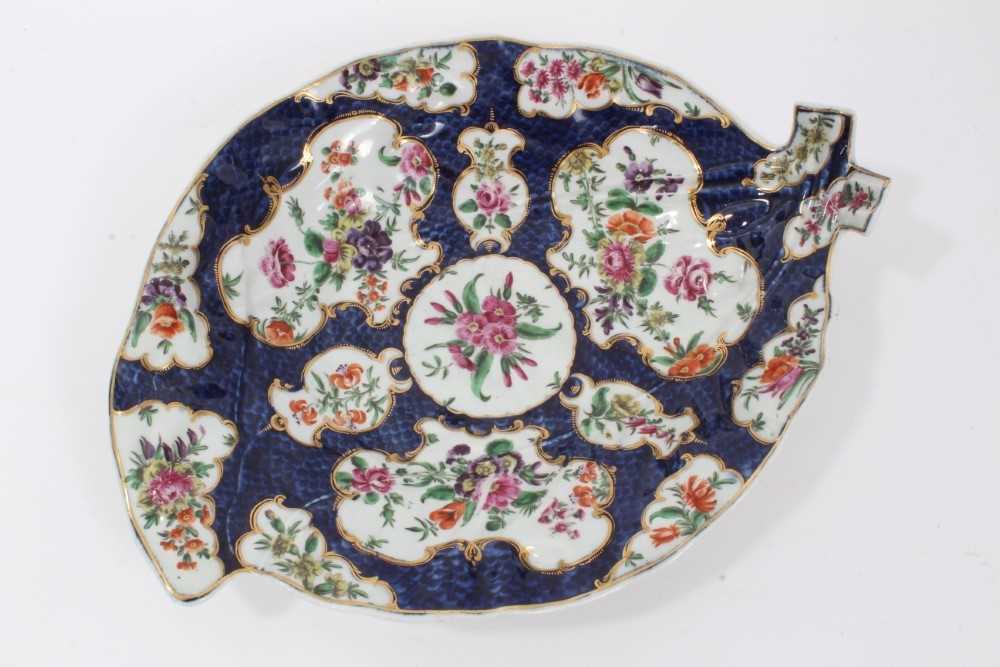 Lot 70 - Worcester cabbage leaf dish, circa 1770, painted with panels of flowers with gilt scrollwork borders, on a blue scale ground, seal mark to base, 26cm long