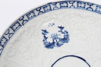 Lot 80 - Lowestoft blue and white saucer, circa 1765, relief moulded, with circular panels containing Chinese landscapes and a patterned border, 12.25cm diameter