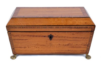Lot 778 - Regency satinwood and kingwood crossbanded tea caddy of sarcophagus form with rosewood cross banded decoration, ebony stringing and brass lion mask handles, raised on brass paw feet.