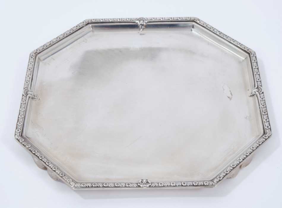 Lot 328 - 1930s silver salver of octagonal form with a floral border on four wing feet (Sheffield 1932)