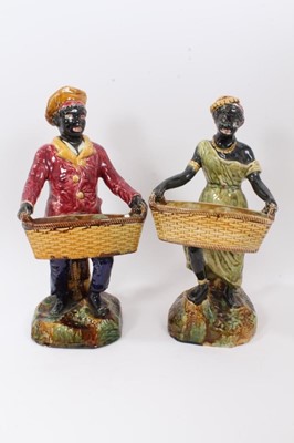 Lot 246 - Pair of continental majolica figures, late 19th century, shown holding baskets and standing on grassy bases, 36cm and 38cm high