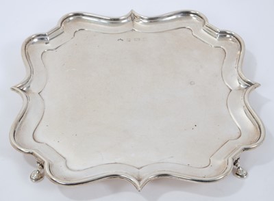 Lot 379 - Early George V silver salver of shaped square form, with piecrust border, on four hoof feet