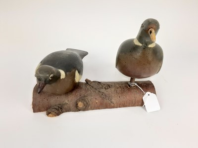 Lot 991 - Two painted wooden decoy pigeons mounted on a log