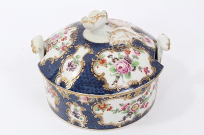 Lot 193 - Worcester butter tub and cover, circa 1770, painted with flowers in gilt scrollwork panels, on a blue scale ground, crescent mark to base, 11cm diameter