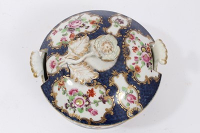 Lot 193 - Worcester butter tub and cover, circa 1770, painted with flowers in gilt scrollwork panels, on a blue scale ground, crescent mark to base, 11cm diameter