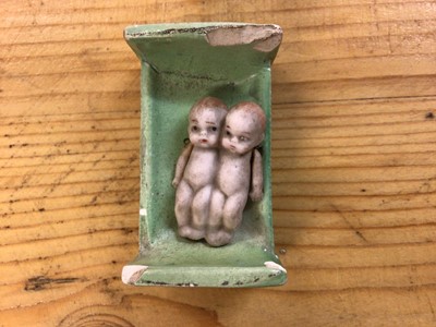 Lot 2429 - Dolls - German Bisque Conjoined miniature twins with pin jointed arms, in miniature green ceramic bed.