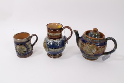 Lot 1174 - Doulton Lambeth stoneware commemorative items, including an Edward VII teapot, Edward VII silver mounted mug, and a Queen Victoria jug (3)