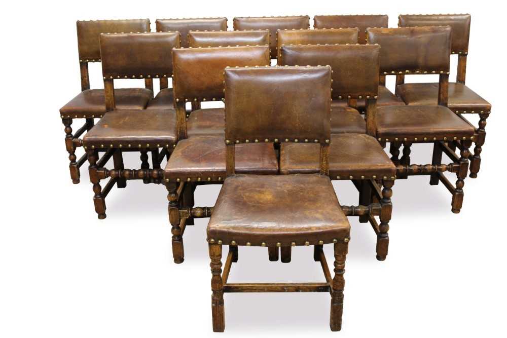 Lot 1429 - Set of twelve Cromwellian style oak and brown leather dining chairs with padded backs and seats and brass studded leather upholstery