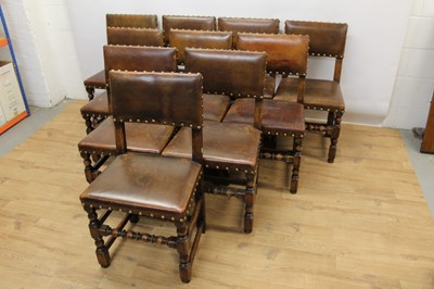 Lot 1429 - Set of twelve Cromwellian style oak and brown leather dining chairs with padded backs and seats and brass studded leather upholstery