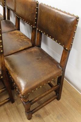 Lot 1429 - Set of twelve Cromwellian style oak and brown leather dining chairs with padded backs and seats and brass studded leather upholstery