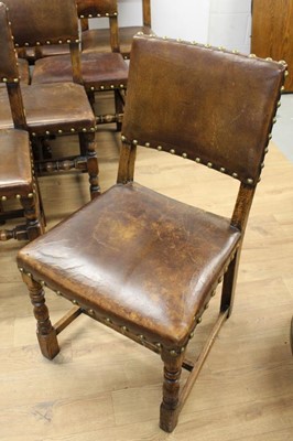 Lot 1429 - Set of twelve Cromwellian style oak and brown leather dining chairs with padded backs and seats and brass studded leather upholstery