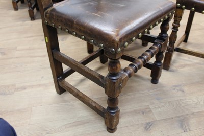 Lot 1429 - Set of twelve Cromwellian style oak and brown leather dining chairs with padded backs and seats and brass studded leather upholstery