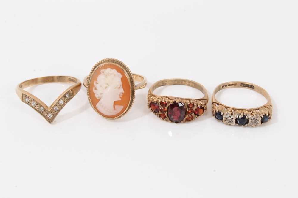 Lot 22 - Four 9ct gold rings to include 1970s sapphire and diamond five stone ring in carved scroll setting, similar style garnet ring, diamond set wishbone ring and cameo ring